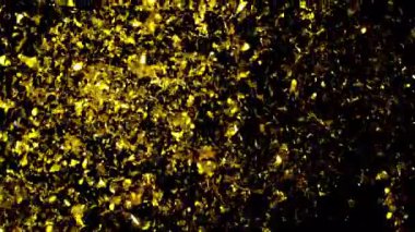 Zarif metalik altın konfetileri yavaş çekimde karanlık bir arkaplana doğru düşüyor, parıldayan, kutlayıcı bir atmosfer yaratıyor.