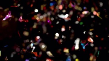 Metalik konfetilerin göz kamaştırıcı patlaması karanlık bir zemin üzerinde parlayan renklerle canlı ve şenlikli bir atmosfer yaratır.