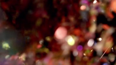 Işıldayan konfeti havada zarafetle sürükleniyor, karanlık bir arka plana karşı ışıl ışıl bir etki yaratıyor.