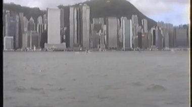 Victoria Limanı 'ndaki bir tekneden Hong Kong' un ufuk çizgisine baktığımızda arka planda büyük bir dağ bulunan yüksek gökdelenlerin yoğun bir şehir manzarasını görüyoruz.