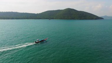 Nefes kesici bir drone görüntüsü, Tayland 'ın çarpıcı mavi sularında süzülen uzun kuyruklu bir tekneyi yakalar ve bu tropikal cennetin dingin güzelliğini gösterir.