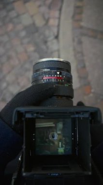 Bir fotoğrafçı, şehir manzarasını klasik bir dokunuşla yakalayarak, bir film kamerasının görüş açısıyla karmaşık sokak mimarisini çerçeveler.