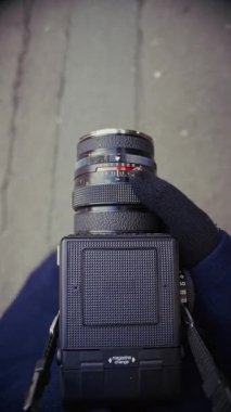 Bir fotoğrafçı sokaklarda yürüyor, klasik bir kameranın görüş açısını nazikçe kapatıyor, şehir keşiflerinin özünü yakalıyor.