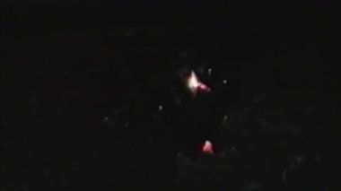 Kıvılcım saçan közleri ve titreyen küçük bir alevi olan loş bir şömine, etrafındaki karanlığa karşı yumuşak ve minimal bir parıltı yayarak sessiz ve bastırılmış bir atmosfer yaratır.
