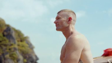 Bir gezgin, açık mavi gökyüzünün altındaki bulanık kireçtaşı kayalıklarıyla çerçevelenmiş Tayland 'da geleneksel bir tekne yolculuğunun keyfini çıkarıyor.