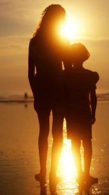 Bir abla, erkek kardeşlerinin omzuna sarılır. Huzurlu bir okyanus günbatımına karşı siluetlenirler. Yürekten bir kardeş sevgisi ve bağ kurma anı yakalarlar.