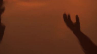 Siluetli el ele tutuşmalar, ıslak kumsalda yansımalar, kıyıya yansıyan ılık bir parıltı.