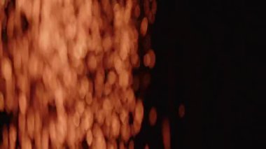 Büyüleyici bir bokeh ateşi gösterisi karanlığın içinde yavaşça sürüklenen kıvılcımlar oluşturur. Parlak, ruhani bir ortam yaratır.
