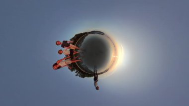 Çocuklar el ele tutuşurken kumsalda huzurlu bir yürüyüşün tadını çıkarırlar. 360 küçük gezegen manzarası o anın huzurunu ve neşesini vurgular.