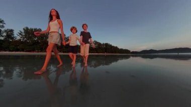 Çocuklar kumsalda el ele yürürken birbirlerine bağlanırlar. Yürek ısıtan bir birliktelik ve sakinlik anı yakalarlar.