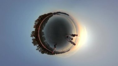 Küçük bir gezegen manzarası, bir baba ve çocuklarının parıldayan, ıslak bir sahil kıyısında koşarken neşeli bir anı yakalar.