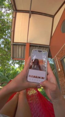 Bir hamakta uzanmış, huzurlu ve odaklanmış bir anı gösteren bir resmi düzenlemek için telefon kullanma POV 'u
