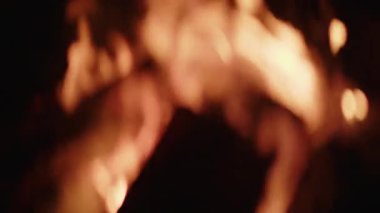 Karanlığın içinde ılık turuncu kıvılcımlar süzülürken, gece ateşinden gelen bulanık alevlerin yumuşak odak noktası, sakin ve atmosferik bir manzara yaratıyor.