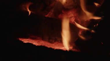 Huzurlu bir kamp ateşi sahnesi, odunların yavaşça yandığı, yumuşak, titreyen alevlerin yaydığı, rahatlatıcı, rahat bir atmosfer yaratan.