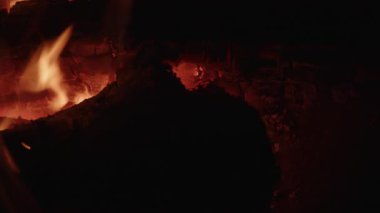 Odun, sakin bir kamp ateşinde parlak alevlerle aydınlatılır. Sıcak ve sakin bir atmosfer yaratır.