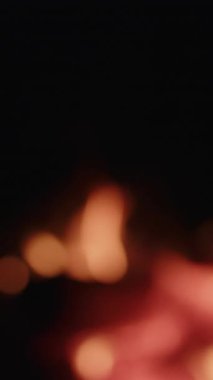 Yumuşak, bulanık bir şenlik ateşi gece gökyüzüne karşı sıcak bokeh daireler oluşturur, huzurlu ve samimi bir ortam sunar.