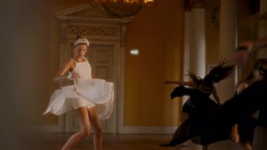 Genç dansçılar, parlak ve zarif bir odada beyaz elbiseli ve tacının ön planda durduğu, karmaşık mimari detaylarla süslenmiş çağdaş bir dans gösterisi yapıyorlar.