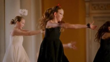 Çağdaş bir dans gösterisi, dinamik hareketler içinde dansçıların olduğu, çarpıcı bir kostüm, kanatlı beyaz bir melek kıyafeti ve süslü bir korna ile siyah şeytani bir kıyafet