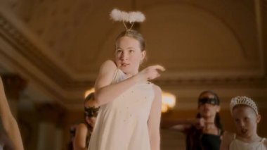 Çağdaş bir dans gösterisi büyük bir balo salonunda başlıyor, beyaz elbiseli bir kız ve odak noktası olarak tüylü bir başlık, zarif ve anlamlı bir rutin uyguluyor.