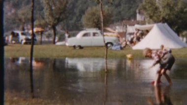 8 mm 'lik bir çocuk, su birikintisinde oyuncak teknesiyle neşeyle oynarken kaygısız bir eğlence ve masumiyet anını yakalıyor.