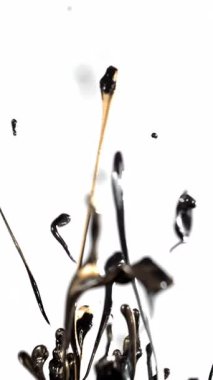 Yavaş çekimde siyah boya beyaz arka plana sıçrayıp yayılıyor, dinamik ve büyüleyici zıtlıklar yaratıyor.