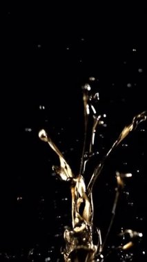 Metalik altın boya yavaş çekimde siyah arka plana çarpıcı ve zarif bir soyut etki yaratır.