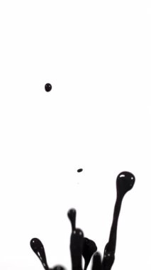 Soyut siyah boya, temiz beyaz bir arkaplana karşı dinamik ve akışkan bir hareket yaratarak havada zarifçe süzülüyor.