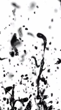 Siyah boya beyaz arka planda yavaş çekimde sıçrar, dramatik bir kontrastla dinamik, soyut desenler yaratır.