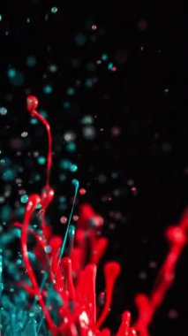 Canlı mavi ve kırmızı boyalar siyah bir arkaplan üzerinde yüzer, cesur ve soyut bir görsel etki yaratır.