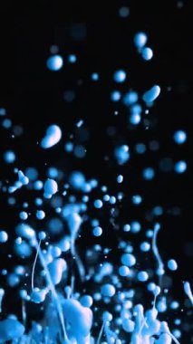 Canlı bir mavi boya serpintisi, siyah arka plana karşı yavaş çekimde zarifçe yükselir ve çarpıcı ve dinamik bir görsel etki yaratır.