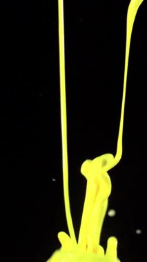 Canlı bir sarı boya sersemletici ağır çekimde çekilir, karanlık bir arkaplana karşı dinamik bir patlama yaratır.