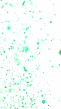 Canlı, neon yeşil bir boya beyaz bir zemin üzerinde fışkırır, yüzen damlacıklar cesur, sanatsal bir etki yaratmak için havada asılı kalır.