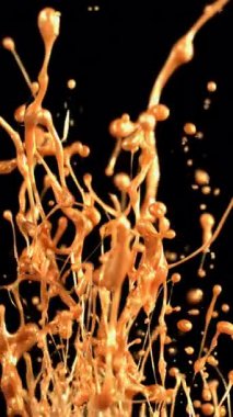 Büyüleyici bir ağır çekim, metalik altın akışkan patlamasını yakalıyor, havaya püskürtüyor ve ışık ve hareketle parıldayan zarif, yüzen damlacıklar oluşturuyor.