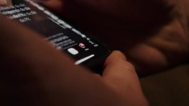 Cep telefonu ekranındaki sosyal medya kaynaklarında gezinen ellerin yakın plan görüntüleri