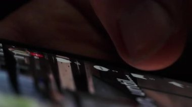 Bir kişinin eli hızlı bir şekilde akıllı telefon ekranındaki sosyal medya iletilerini tarar, güncellemeleri ve içeriği tarar