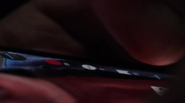 Bir kişi akıllı telefon ekranındaki iletilerle kaydırma ve etkileşim kurarak sosyal medya içeriğine bağlanır