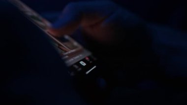 Bir kişi sosyal medya beslemesini akıllı telefon ekranında kontrol eder, iletiler ve güncellemeler arasında kaydırır