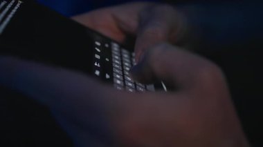 Sönük bir ayarda akıllı bir telefona mesaj yazan ellerin yakın plan görüntüsü