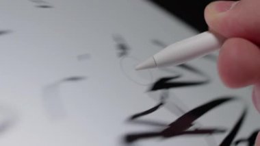 Dokunmatik ekran tabletinden rastgele karalamalar silen bir stil kalemin yakın plan görüntüsü, dijital düzenleme sürecini gerçek zamanlı olarak gösterir