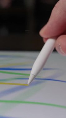 Tablet ekranına rastgele karalamalar çizmek için stil kalem kullanan bir elin yakın çekimi, yaratıcı ve özgür bir dijital çizim sürecini gösterir
