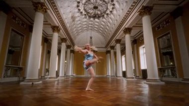 Dolly, gece elbisesi giymiş bir dansçının, klasik bir balo salonunda, parke döşemesi parke döşemeli bir şekilde, dansının zarafetini ve akışkanlığını yakaladığı sahneyi yakınlaştır.