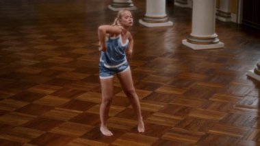 Gece elbisesi içinde çıplak ayaklı, çağdaş bir dansçının, klasik bir salonun parke zemininde dans ederken yüksek açılı bir fotoğrafı.