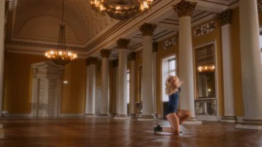 Genç bir kız yüksek topuklularla büyüleyici çağdaş bir dans sergiliyor. Modern hareketleri klasik, sofistike bir salonda zarafetle harmanlıyor.