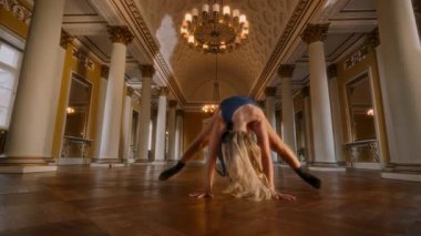 Topuklu giyen genç bir kız, enerji ve zarafeti harmanlayan lüks bir salonda dinamik ve zarif bir dans gösterisi sunuyor.