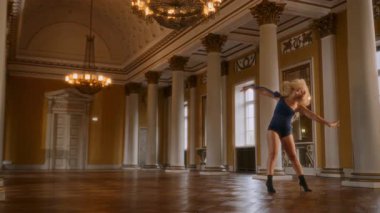 Genç bir kadın zarif bir balo salonunda sofistike bir dans gösterisi sergiliyor.
