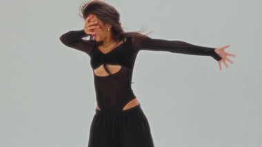 Siyah elbiseli bir kızın etkileyici bir solo dans gösterisi. Parlak, minimalist bir stüdyoda akışkan ve duygusal hareketler sergiliyor.
