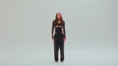 Siyahlı genç bir dansçı, minimalist beyaz bir stüdyoda ham duygular ve akışkan hareketler sergiliyor.