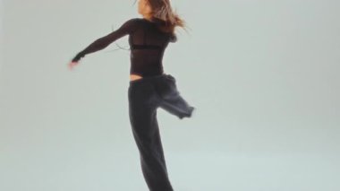 Siyahlar içinde çağdaş bir dansçı parlak, minimalist bir stüdyoda zarif bir dönüş gerçekleştirir.