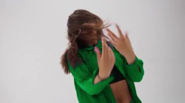 Genç bir dansçı, temiz beyaz bir stüdyoda canlı bir renk değiştiren kostüm giyerek hareketlerle güçlü duygular ifade eder.