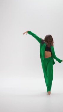 Genç bir dansçı, hareketleriyle renk değiştiren termokromik bir kostümle, beyaz bir stüdyonun parlak, minimalist arka planına karşı enerjik bir gösteri sergiliyor.